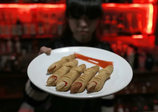 A waitress shows cookies in the shape of chopped fingers which is served at the V bar during a photo opportunity in Beijing November 28, 2014. The Vampire-themed bar serves unique foods such as a chocolate in the shape of an eyeball and cocktails in syringes and blood bags, in a place decorated like a vampire base of the Middle Ages. (Photo by Kim Kyung-Hoon/Reuters)