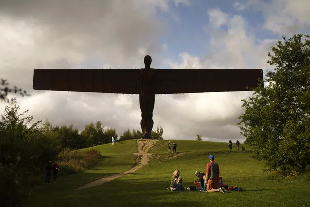A family enjoy a picnic next to the Angel of the North on September 19, 2020 in Gateshead, United Kingdom. Since easing its first nationwide lockdown in May, England has imposed localised lockdown rules on towns across the Midlands and North, in what the prime minister termed a "whac-a-mole" approach to battling Covid-19 flare-ups. Last weekend, almost two million people in Newcastle and surrounding areas were banned from meeting other households, and pubs and restaurants were told to close by 10pm. As the UK government implements similar rules across England, a tour through the towns with local lockdowns shows how Britons are coping with the government's lurching response to the pandemic. (Photo by Christopher Furlong/Getty Images)
