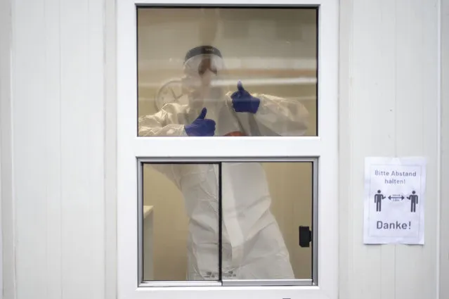 An employee shows thumbs-up inside a container at the test center for the coronavirus at Central Station in Cologne, Germany, Friday, October 23, 2020. According to the Robert Koch Institute, Germany's federal government agency and research institute responsible for disease control and prevention, the number of new infections with the corona virus in Cologne has risen to 120.1 per 100,000 inhabitants. (Photo by Marius Becker/dpa via AP Photo)