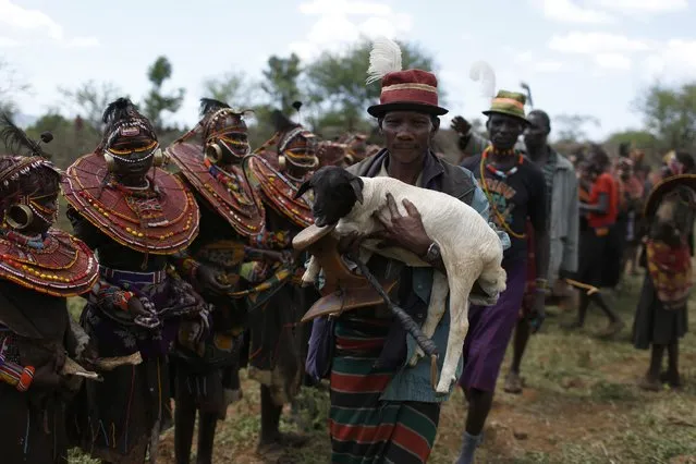 A Pokot man holds a lamb as he blesses over a hundred girls during an initiation ceremony marking the girls' passing over into womanhood, about 80 km (50 miles) from the town of Marigat in Baringo County December 6, 2014. (Photo by Siegfried Modola/Reuters)