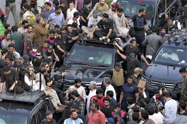 Security personnels and supporters move with a vehicle, center, carrying Pakistan's former Prime Minister Imran Khan during an election campaign rally, in Lahore, Pakistan, Monday, March 13, 2023. Khan rallied thousands of supporters in eastern Pakistan on Monday as courts in the capital, Islamabad, issued two more arrest warrants for him over his failure to appear before judges in graft and terrorism cases, officials said. (Photo by K.M. Chaudary/AP Photo)