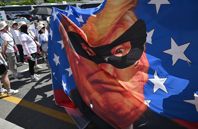 South Korean protesters carry a big banner showing a caricature of US President Donald Trump as a robber during a rally against Trump's tariff policy near the US embassy in Seoul on July 27, 2025. South Korea's deputy prime minister will meet with US Treasury Secretary Scott Bessent next week, ahead of Washington's deadline to reach a trade deal, Seoul's presidential office said on July 26. (Photo by Jung Yeon-je/AFP Photo)
