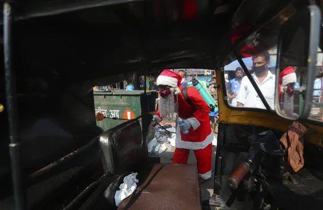 A man dressed as Santa Claus sanitizes an autorickshaw in Dharavi, one of Asia's biggest slums, in Mumbai, India, Saturday, December 19, 2020. India's coronavirus cases have crossed 10 million with new infections dipping to their lowest levels in three months, as the country prepares for a massive COVID-19 vaccination in the new year. (Photo by Rafiq Maqbool/AP Photo)