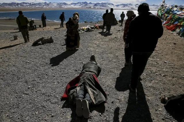 A Tibetan man prostrates himself as others circle around a rock above Namtso lake in the Tibet Autonomous Region, China November 17, 2015. (Photo by Damir Sagolj/Reuters)