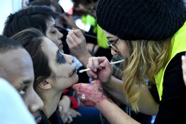 A woman puts makeup on people participating in the annual “Zombie Walk” in Bordeaux on October 22, 2016. (Photo by Georges Gobet/AFP Photo)