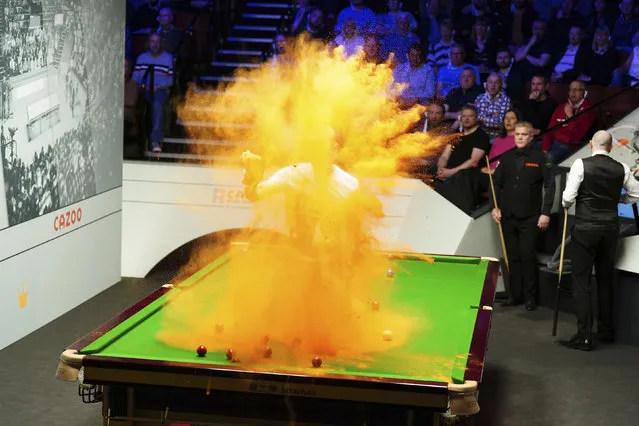 A 'Just Stop Oil' protester jumps on the table and throws orange powder during the match between Robert Milkins against Joe Perry as part of day three of the World Snooker Championship at the Crucible Theatre, Sheffield, Britain, Monday, April 17, 2023. (Mike Egerton/PA Wire via AP Photo)