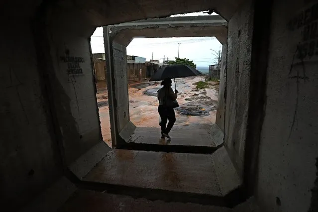 A resident walks between concrete structures after it rained in the Sol Nascente favela of Brasilia, Brazil, Tuesday, March 21, 2023. Sol Nascente, which means Rising Sun, suffers poor public transport and has unpaved, impassable roads, which flood frequently during the months of summer rains. (Photo by Eraldo Peres/AP Photo)