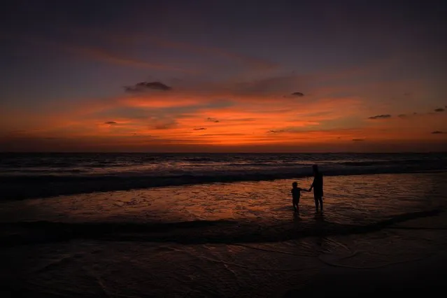 A boy holds hand of his father as they watch the sun set at a beach in Goa, India, Wednesday, May 3, 2023. India’s picturesque state of Goa is scheduled to host the Shanghai Cooperation Organization (SCO) ministers meet on Friday. (Photo by Manish Swarup/AP Photo)