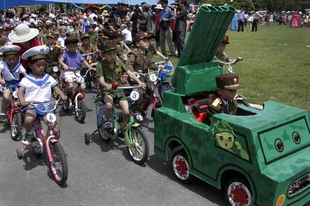 North Korean children, dressed as military service members, ride tricycles behind a toy vehicle designed to look like a mobile rocket launcher during a day of games and a parade to mark the International Children's Day at Mangyongdae Amusement Park on the outskirts of Pyongyang on Saturday, June 1, 2013. (Photo by Jon Chol Jin/AP Photo)