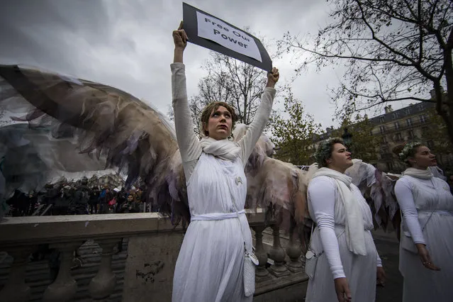 Protestors dressed as angels hold signs as they participate in the human chain demonstration at Republique Square on the eve of the COP21 Conference opening, Paris, France, Sunday, November 29, 2015. (Photo by Ian Langsdon/EPA)