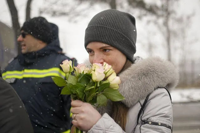 A refugee fleeing the conflict from neighbouring Ukraine smells a bouquet of roses, on International Women's Day, at the Romanian-Ukrainian border, in Siret, Romania, Tuesday, March 8, 2022. It is a global day to celebrate women, but many fleeing Ukraine feel only the stress of finding a new life for their children as husbands, brothers and fathers stay behind to defend their country from Russia's invasion. (Photo by Andreea Alexandru/AP Photo)