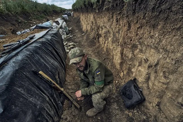 A Ukrainian soldier sits in a trench at the frontline near Bakhmut in the Donetsk region, Ukraine, Monday, May 22, 2023. (Photo by Libkos/AP Photo)