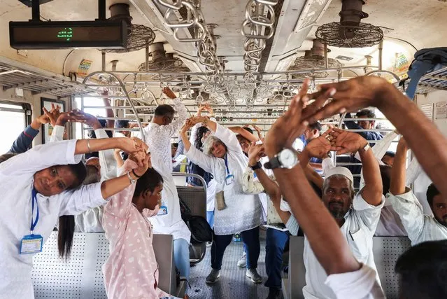 People perform yoga in a local train, during International Yoga Day in Mumbai, India on June 21, 2023. (Photo by Francis Mascarenhas/Reuters)