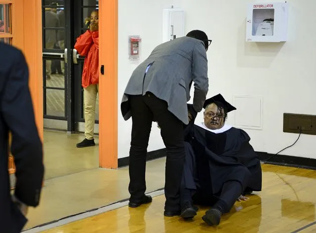 A young girl (L) reacts as a man helps up the Rev. Jesse Jackson after he tripped over a cable and fell to the floor while arriving to address graduates at the winter commencement exercises at Morgan State University in Baltimore, December 18, 2015. Jackson was uninjured from the fall and went on to address the graduates as planned. (Photo by Bryan Woolston/Reuters)