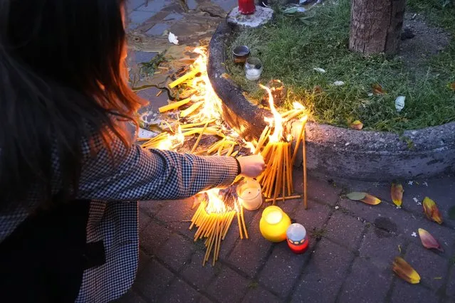 People light candles for the victims near the Vladislav Ribnikar school in Belgrade, Serbia, Wednesday, May 3, 2023. Police say a 13-year-old who opened fire at his school drew sketches of classrooms and made a list of people he intended to target. He killed eight fellow students and a school guard before being arrested. (Photo by Darko Vojinovic/AP Photo)