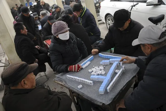 A woman wearing a mask plays mahjong with other residents near a street amid heavy smog in Jinan, Shandong province, China, December 22, 2015. (Photo by Reuters/China Daily)