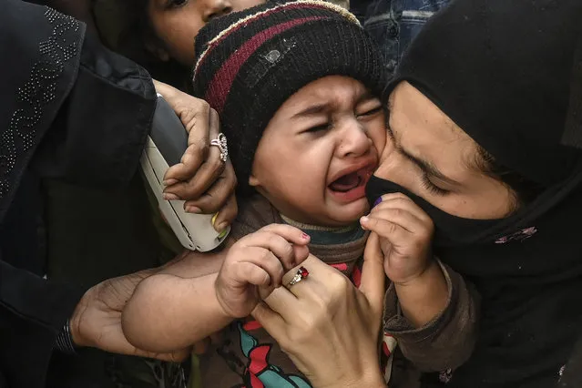 A child reacts as a health worker administers an Inactivated polio vaccine (IPV) during a polio vaccination campaign in Lahore on March 2, 2021. (Photo by Arif Ali/AFP Photo)