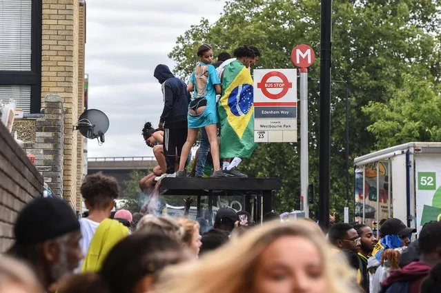 Revellers dance on top of a bus shelter during the Notting Hill Carnival Adults Parade in London, Britain, 27 August 2018. The Adult Parade is billed as the crescendo to the two-day street carnival, which celebrates Caribbean heritage, and this year the festival's 52nd anniversary. (Photo by Pete Maclaine/EPA/EFE)