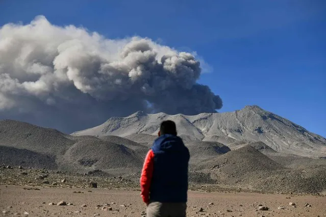 A man watches a smoke and ash stack rise from the Ubinas volcano's crater, located in the Moquegua region in southern Peru, on July 5, 2023. Peru's Ubinas volcano, active again after four dormant years, blew its top twice on July 4, showering nearby towns with ash, the country's IGP geophysical institute said. (Photo by Diego Ramos/AFP Photo)