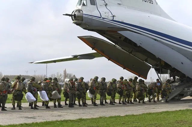 Russian paratroopers load into a plane for airborne drills during maneuvers in Taganrog, Russia, Thursday, April 22, 2021. Russia's defense minister on Thursday ordered troops back to their permanent bases following massive drills amid tensions with Ukraine, but said that they should leave their weapons behind in western Russia for another exercise later this year. (Photo by AP Photo/Stringer)
