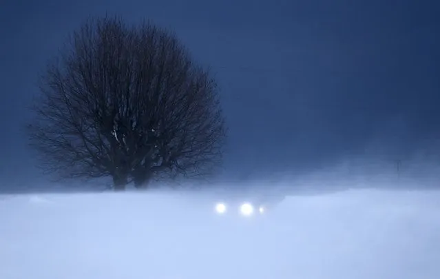 The lights of a car are seen through a gust of wind on a secondary road in Lussy near Lausanne February 5, 2015. (Photo by Denis Balibouse/Reuters)
