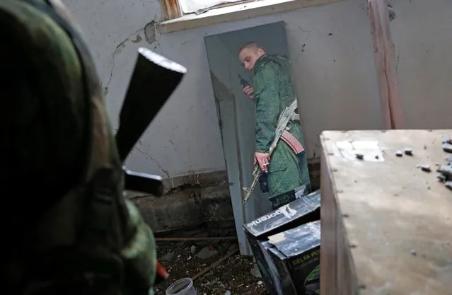 A militant of the self-proclaimed Luhansk People's Republic (LNR) is reflected in a mirror at fighting positions on the line of separation from the Ukrainian armed forces in Luhansk Region, Ukraine on April 21, 2021. (Photo by Alexander Ermochenko/Reuters)