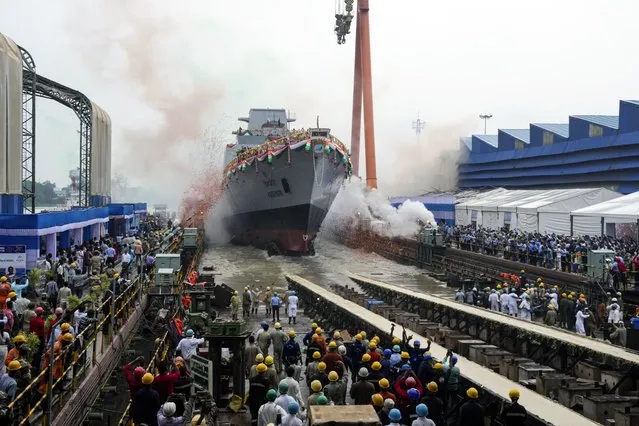 Confetti and smoke in the colors of the Indian national flag mark the entry of INS Vindhyagiri, a new warship for the Indian navy, into the Hooghly river in Kolkata, India, Thursday, August 17, 2023. This P17A series warship, built by the Garden Reach Shipbuilders and Engineers in Kolkata, was launched by the Indian President Droupadi Murmu Thursday. (Photo by Bikas Das/AP Photo)