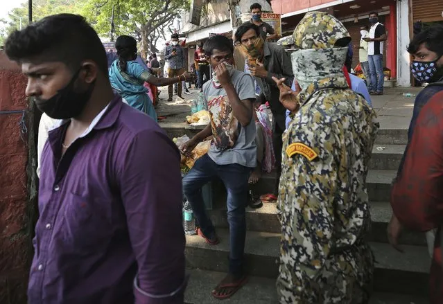 A municipal official, second right, reprimands street vendors for not wearing face masks properly during a lockdown imposed due to rising number of COVID-19 cases in Bengaluru, India, Wednesday, April 28, 2021. India, a country of nearly 1.4 billion people, Wednesday became the fourth nation to cross 200,000 deaths. (Photo by Aijaz Rahi/AP Photo)