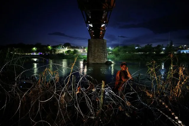 A migrant from Venezuela, part of a large group who crossed after sundown, waits behind razor wire after crossing the Rio Grande into the United States in Eagle Pass, Texas, U.S., September 26, 2023. (Photo by Brian Snyder/Reuters)