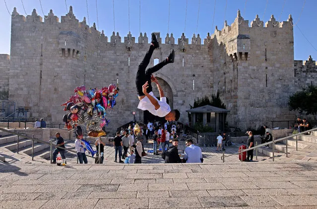 A Palestinian youth performs a jump outside the Damascus Gate in Jerusalem's Old City on May 13, 2021 during Eid al-Fitr, which marks the end of the holy fasting month of Ramadan. (Photo by Ahmad Gharabli/AFP Photo)
