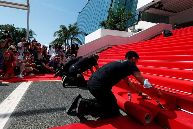 Photographers and cameramen watch as workers install the red carpet in front of the main entrance of the Festival Palace before the opening ceremony of the 74th Cannes Film Festival in Cannes, France on July 6, 2021. (Photo by Johanna Geron/Reuters)