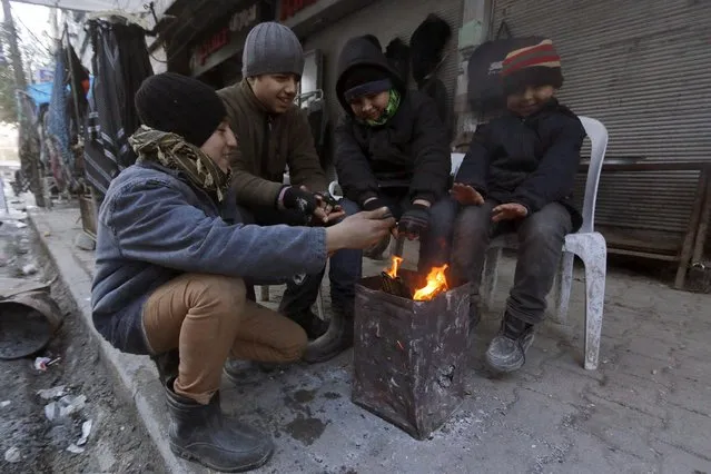Boys warm themselves around a fire in Aleppo January 9, 2015. (Photo by Hosam Katan/Reuters)