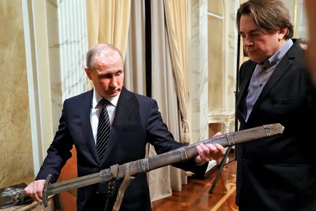Russia's President Vladimir Putin holds a sword during a meeting with the “Viking” film crew, as film producer and Director General of Channel One Russia Konstantin Ernst (R) looks on, in Moscow, Russia December 30, 2016. (Photo by Mikhail Klimentyev/Reuters/Sputnik/Kremlin)