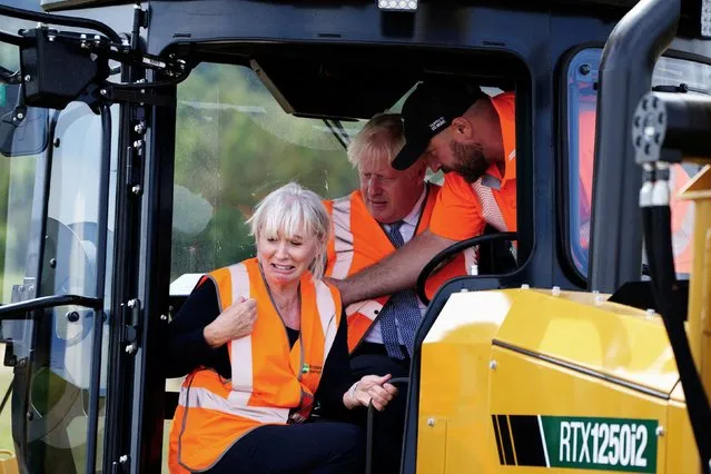 Britain's Prime Minister Boris Johnson (R) and Britain's Culture Secretary Nadine Dorries (L) sit in mole plough during a visit of the Henbury Farm in north Dorset, on August 30, 2022 as Wessex Internet company is laying fibre optics in the field. Boris Johnson's visit marks a new data showing that 70 percent of the United Kingdom is now benefiting from gigabit broadband coverage. (Photo by Ben Birchall/Pool via AFP Photo)