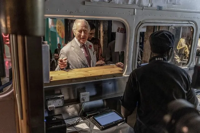 Britain's King Charles III (C) orders food from a food truck during a visit to Nairobi Street Kitchen in Nairobi on November 1, 2023. Britain's King Charles III visits the Nairobi Street Kitchen to celebrate the Kenyan cultural and creative scene, where he met with young creatives including artisans, fashion designers, musicians and artists. (Photo by Luis Tato/AFP Photo)
