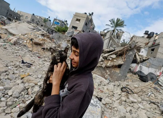 A Palestinian child holds a cat, while standing on the rubble of houses destroyed in Israeli strikes during the conflict, amid the temporary truce between Hamas and Israel, at Khan Younis refugee camp in the southern Gaza Strip on November 27, 2023. (Photo by Mohammed Salem/Reuters)