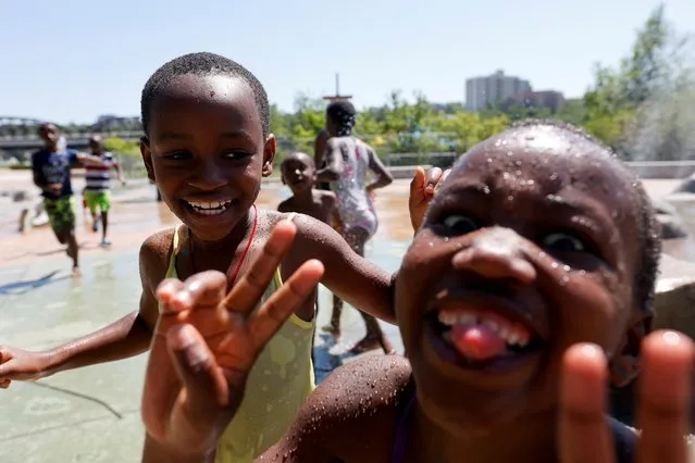 Kids play in water to cool off during the scorching weather of a heatwave at a River Landing splash park in Saskatoon, Saskatchewan, Canada July 2, 2021. (Photo by David Stobbe/Reuters)