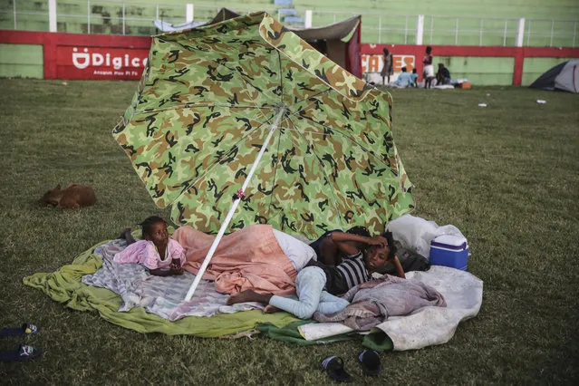 People rest after spending the night at a soccer field following Saturday´s 7.2 magnitude earthquake in Les Cayes, Haiti, Sunday, August 15, 2021. (Photo by Joseph Odelyn/AP Photo)