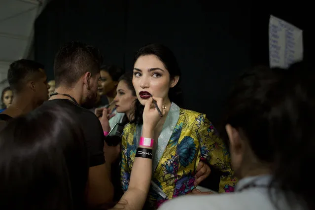 Models get finishing touches put on their makeup as they prepare to take the runway wearing creations by Mexican fashion house Pineda Covalin, at Mercedes-Benz Fashion Week in Mexico City, Tuesday, April 14, 2015. (Photo by Rebecca Blackwell/AP Photo)