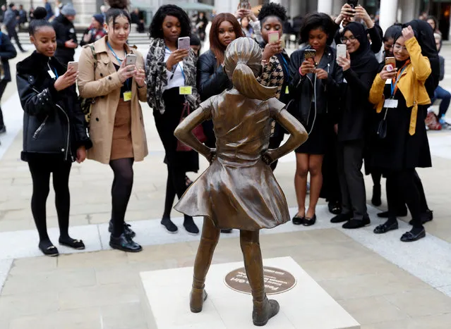 Students from some of London's all girls' schools, take pictures of the “Fearless Girl” statue unveiled by State Street in the financial district of London, Britain, March 5, 2019. (Photo by Peter Nicholls/Reuters)
