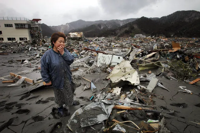 In this March 16, 2011 file photo, Reiko Miura, 68, cries as she looks for her nephew at the tsunami-hit area in Otsuchi, Iwate Prefecture, northern Japan after the March 11, 2011 earthquake and tsunami. “The first two days after the quake struck, I was on a helicopter taking aerial shots. I saw huge columns of black smoke from a flattened town. A large cargo ship was on top of a building. There was no sign of life at all. I did not want to think about thousands of people who were there when the colossal tsunami hit. I just tried to focus on what I needed to do. (Photo by Itsuo Inouye/AP Photo)