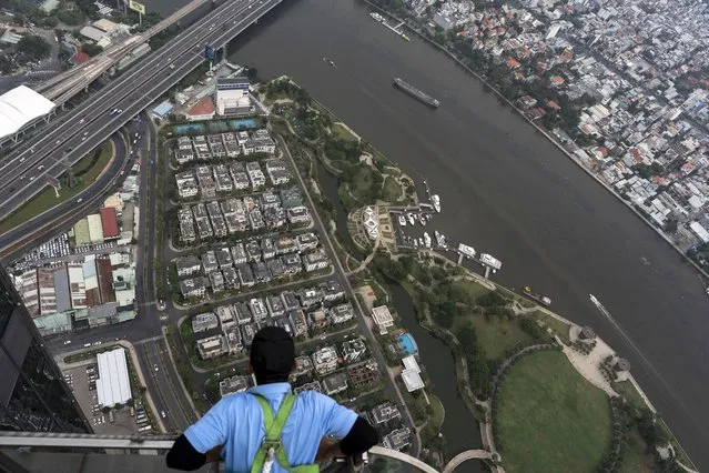 A maintenance worker takes in the view of Ho Chi Minh City, Vietnam, January 21, 2024, as ships cruise along the Saigon River. (Photo by Jae C. Hong/AP Photo)