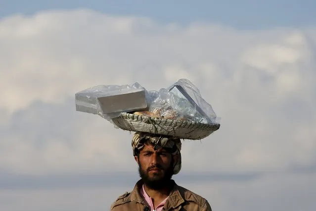 An Afghan man holds sweats for sell on his head in Kabul, Afghanistan March 7, 2016. (Photo by Ahmad Masood/Reuters)