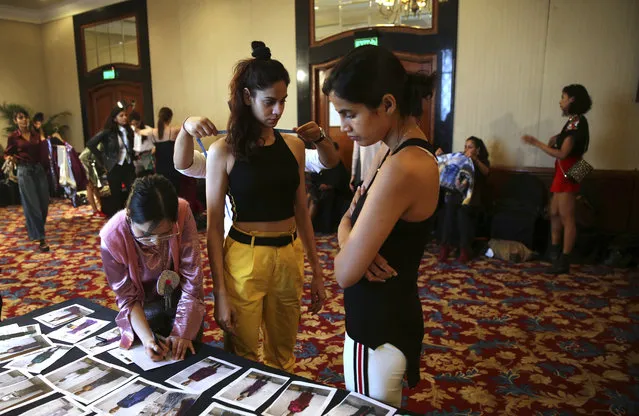 In this Monday, March 11, 2019, photo, a tailor takes measurements of a model as a woman scans photographs during a fitting session ahead of the Lotus Makeup India Fashion Week, in New Delhi, India. Organized by the Fashion Design Council of India, more than 100 of India's top names in fashion and 50 models from India and overseas participated in the five day Lotus Makeup India Fashion Week. (Photo by Manish Swarup/AP Photo)