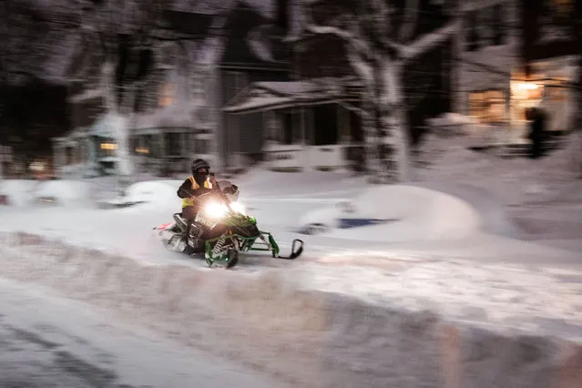 A person rides a snowmobile along a snow covered residential street in Buffalo, New York, on December 25, 2022. US emergency crews counted the grim costs of a colossal winter storm that brought Christmas chaos to millions, especially in hard-hit western New York, where the death toll reached 25 Monday in what authorities described as a “war with mother nature”. (Photo by Joed Viera/AFP Photo)