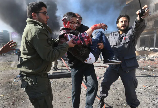 Lebanese men carry an wounded man at the site of an explosion, near the Kuwaiti Embassy and Iran's cultural center, in the suburb of Beir Hassan, Beirut, Lebanon, Wednesday, February 19, 2014. A blast in a Shiite district in southern Beirut killed at least two people on Wednesday, security officials said – the latest apparent attack linked to the civil war in neighboring Syria. (Photo by Hussein Malla/AP Photo)