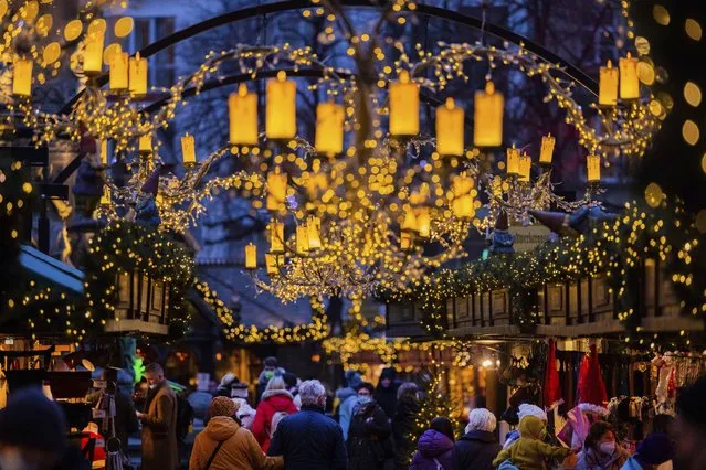 Visitors walk through the Christmas market at Alter Markt, Cologne, Germany, Monday, November 29, 2021. Chancellor Angela Merkel will hold talks Tuesday with the governors of Germany's 16 states amid growing concern about the steep rise in new coronavirus cases in the country. (Photo by Rolf Vennenbernd/dpa via AP Photo)