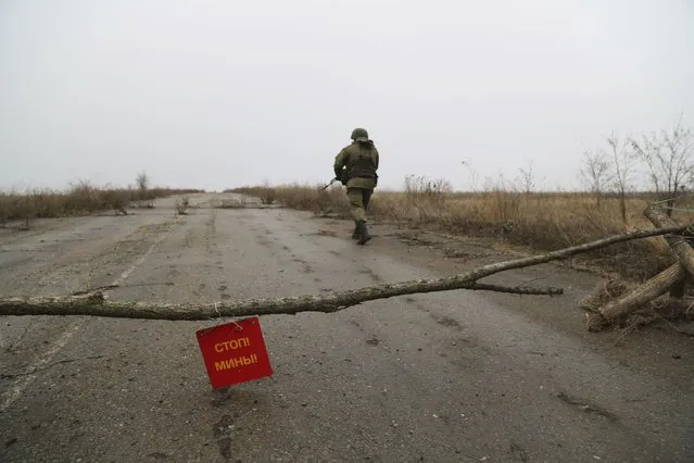 A serviceman walk on a road at the line of separation near Sentianivka, Luhansk region, controlled by Russia-backed separatists, eastern Ukraine, Thursday, December 9, 2021. Russia's military warned the Ukrainian government Thursday against trying to settle a separatist conflict in eastern Ukraine with force, a statement that adds to the tensions sparked by a Russian troop buildup near the Ukrainian border. (Photo by Alexei Alexandrov/AP Photo)