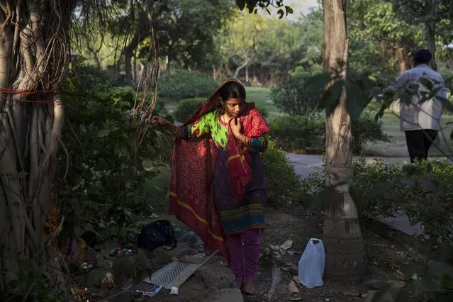 An Indian Hindu woman ties a thread around a banyan tree to seek prosperity and longevity for her husband on Somvati Amavasya in New Delhi, India, Monday, May 18, 2015. (Photo by Tsering Topgyal/AP Photo)