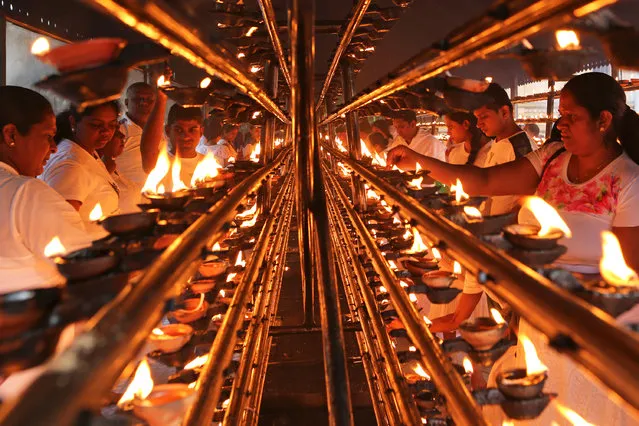 Sri Lankan Buddhist devotees light oil lamps as they mark Poya day or Full Moon Day at a temple on November 22, 2018 in Colombo, Sri Lanka. Buddhists, who make up 60 percent of the country's population, dress in white and perform rituals on Full Moon Day, a public holiday in Sri Lanka. (Photo by Buddhika Weerasinghe/Getty Images)